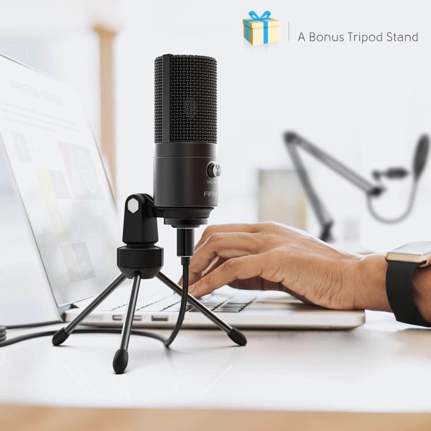 A person types on a laptop keyboard next to a black microphone with a tripod stand on a desk. In the background, there is a blurred image of another microphone and a gift icon with the text “A Bonus Tripod Stand.”.