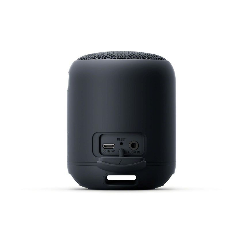 A small, black cylindrical portable speaker is shown from the back, featuring a mesh grill on top, and ports for charging, reset, and audio input near the bottom.