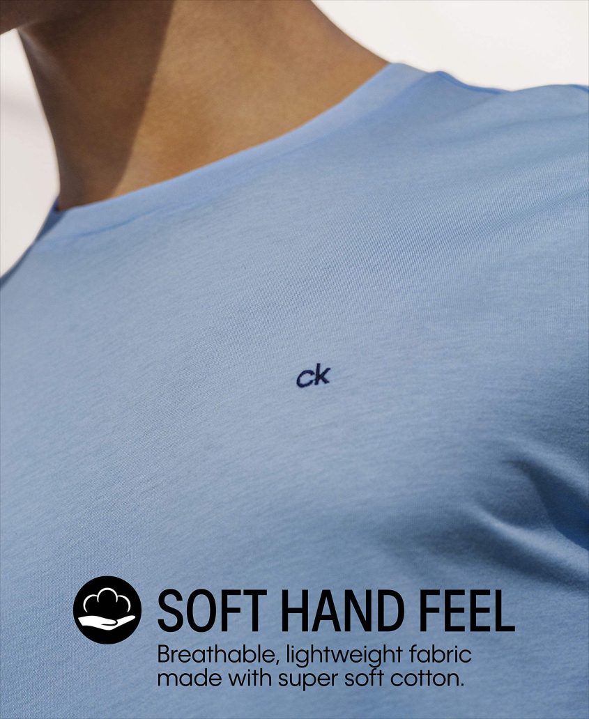 A close-up of a person wearing a light blue Calvin Klein t-shirt with the small ck logo on the chest. Text on the image reads: Soft Hand Feel. Breathable, lightweight fabric made with super soft cotton.