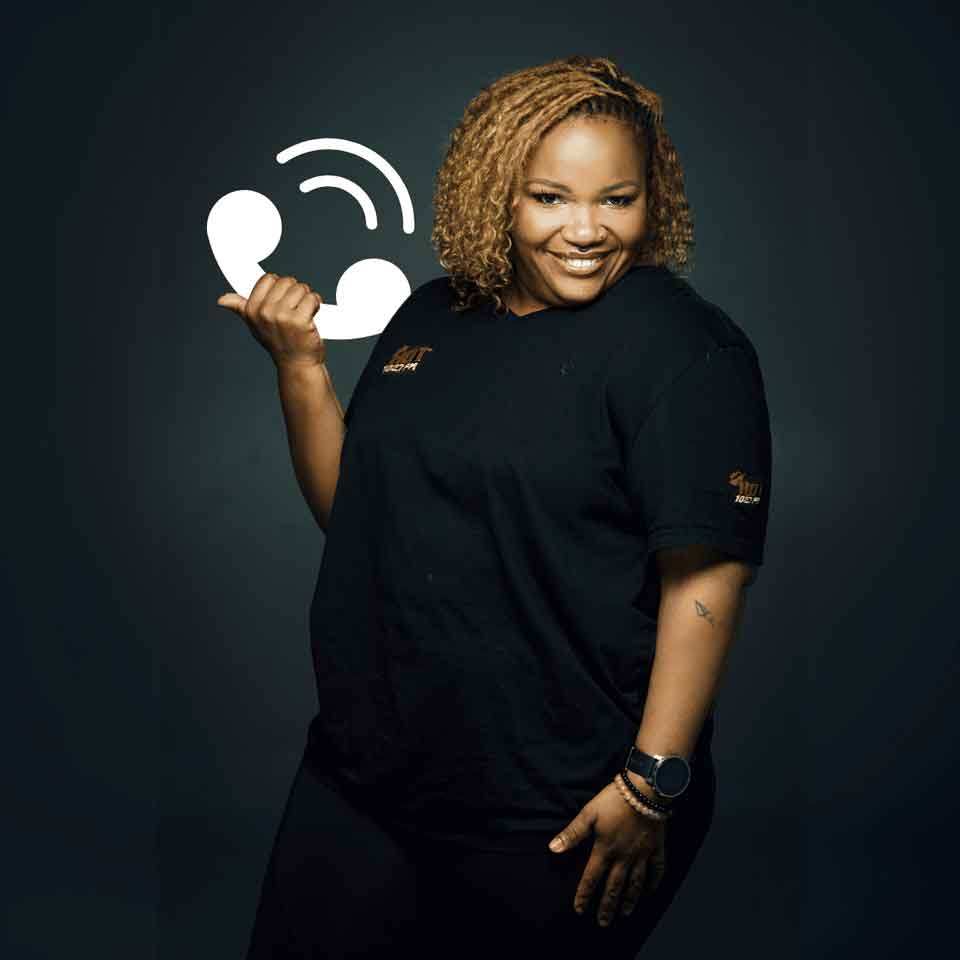 A smiling woman with curly hair wearing a black outfit poses against a dark background, holding up her hand in a phone gesture next to a white phone icon illustration.