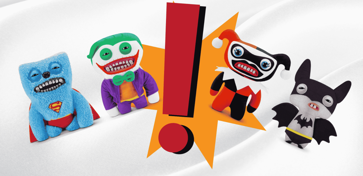 Four plush toys styled as comic book characters—Superman, Joker, Harley Quinn, and Batman—with wide grins stand around a large red exclamation mark on a white wavy background, bringing a playful twist to homeownership décor.