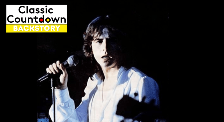 A young man with long hair wearing a white shirt holds a microphone and sings on stage against a dark, blurred background. The Classic Countdown Backstory logo appears in the top left corner of the image.