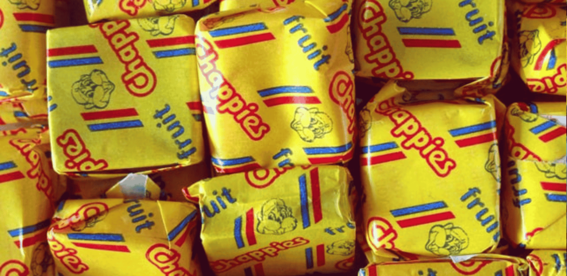 A close-up of several yellow-wrapped Chappies fruit-flavored bubblegum pieces, with colorful red and blue stripes and the Chappies logo printed on the wrappers—classic treats that have sparked fun and unique business opportunities.