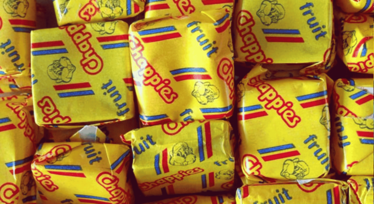A close-up of several yellow-wrapped Chappies fruit-flavored bubblegum pieces, with colorful red and blue stripes and the Chappies logo printed on the wrappers—classic treats that have sparked fun and unique business opportunities.