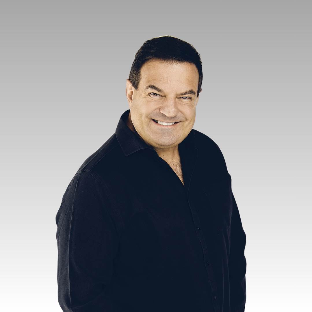 A middle-aged man with short dark hair wearing a black button-up shirt smiles at the camera against a light gray gradient background.