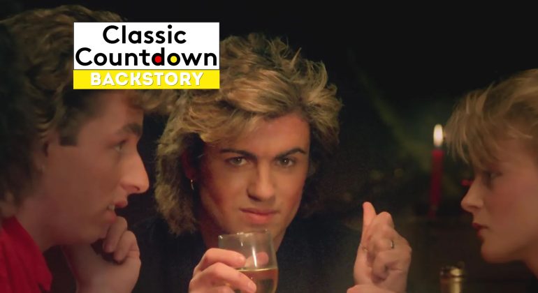 Three people sit together at a table. The center person, with styled blonde hair reminiscent of Prince, looks into the camera holding a glass. The image features a Classic Countdown Backstory logo in the top left corner.