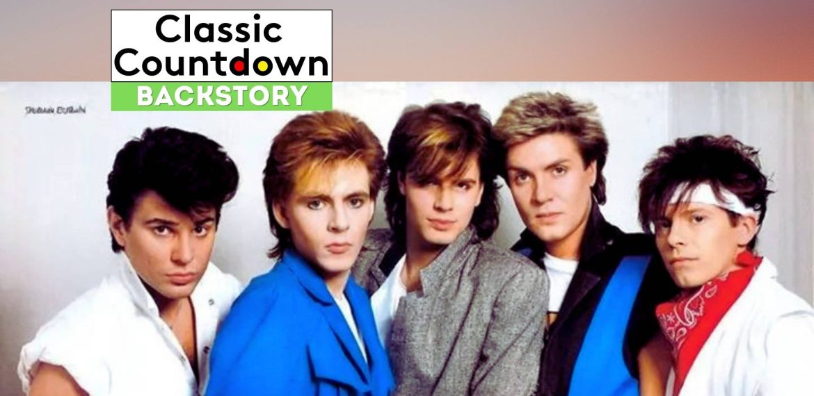 Five men with 1980s hairstyles and colorful outfits pose together against a light background. A banner at the top reads Classic Countdown Backstory, hinting at a nostalgic vibe reminiscent of hits like "Last Christmas.