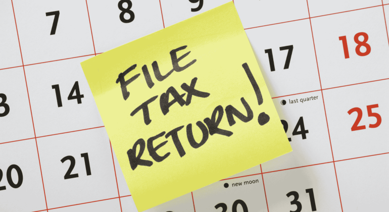 A yellow sticky note with FILE TAX RETURN! written in bold black letters is placed on a calendar, serving as an important reminder for Matric students to stay organized and meet their deadlines.